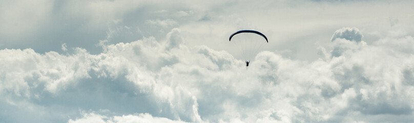 Horizontal cropped image paraglider over cloudy sky background
