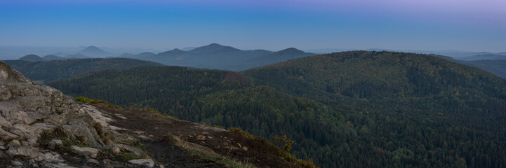 Landscape full of forest before sunrise with morning fog. Forest landscape where peaks of hills are above the fog.