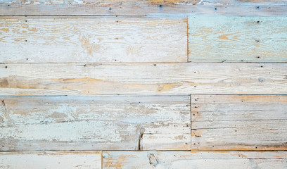 Aged faded reclaimed wood surface with painted boards lined up. Vintage wooden planks on a wall or floor.