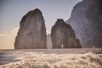 The Faraglioni of Capri behind the wake of a boat, Italy