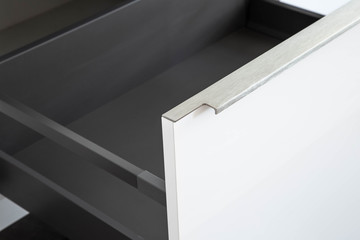 Close-up of a minimal edge straight handle in stainless steel finish on a white glossy kitchen...