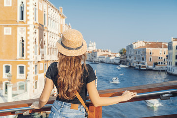 Fototapeta premium Woman in the Venice, standing on the bridge over the grand canal while on sightseeing in a foreign city. Discovery the Venice adventure.