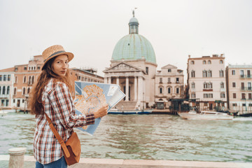 Fototapeta na wymiar Discovery the Venice. Traveler girl looks at the map of walking, female adventure in Venice, Chiesa di San Simeone Piccolo, Italy