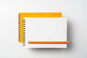two spiral orange notebook and pen on white