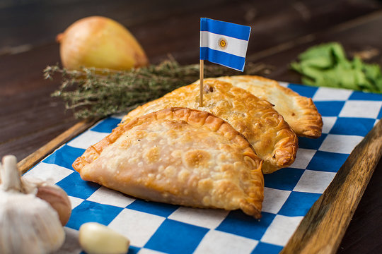 Argentinian empanadas with flag on a dark rustic wooden background