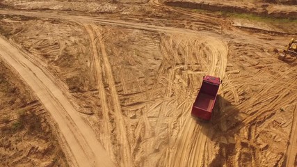 Aerial view of the empty large red truck moving on a sandy track for the sand in desert or dunes. Beautiful view from above.