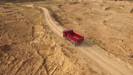 Close-up view the red truck moving on desert or dune track. Beautiful view from above.
