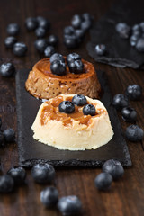 coffee flan and cream pudding with cranberries on black stone tray