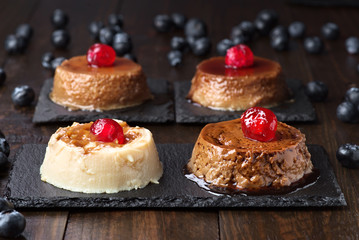 homemade flans of various flavors, with cranberries on a black stone tray
