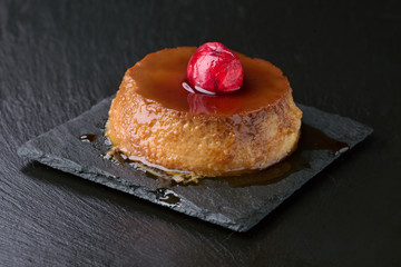 egg custard with caramelized cherries on a black stone tray