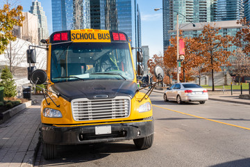 Fototapeta na wymiar School Bus Parked along a Street in a City Centre on a Sunny Autumn Day
