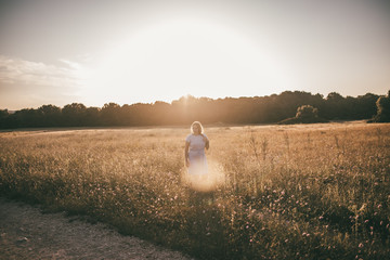 Frau genießt den Sommer beim Spaziergang durch ein Feld