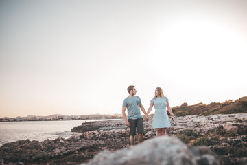 Paar spaziert über Felsen am Strand bei Sonnenuntergang