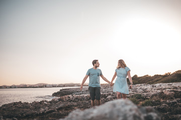 Paar spaziert über Felsen am Strand bei Sonnenuntergang