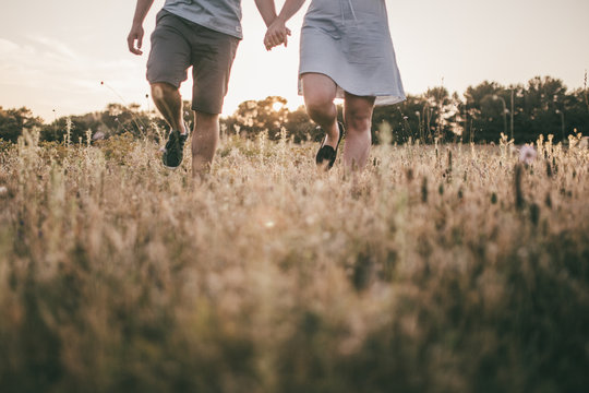 Paar geht Hand in Hand im Feld spazieren