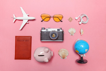 Vacation travel summer weekend adventure trip concept. Minimal simple flat lay with plane vintage camera passport sunglasses globe and shell on pink pastel trendy modern background. Tourist essentials