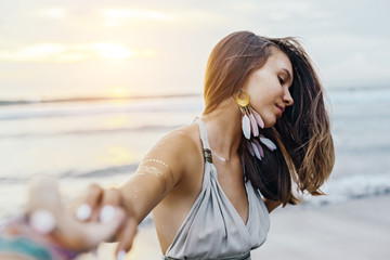 Young girl with silver tattoo and boho jewelry on sunset