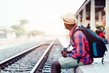 African man traveler standing waiting for the train on railroad station
