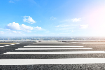 Empty zebra crossing road and city skyline
