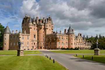 Front lawn of Glamis Castle childhood home of Queen Mother with statues of King James I and Charles I with sun and clouds Scotland UK