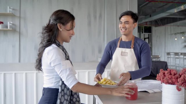 handsome asian waiters wearing apron serving meal and beverage with smile in the cafe