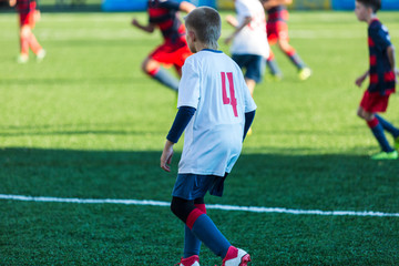 Obraz premium Football training soccer for kids. Boy runs kicks dribbles soccer balls. Young footballers dribble and kick football ball in game. Training, active lifestyle, sport, children activity concept 