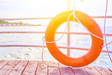 Orange lifebuoy with rope on a wooden pier near sea.