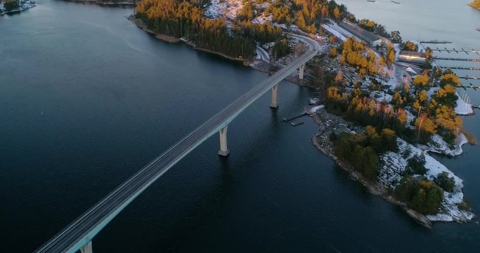 Aerial, reverse, drone shot, of cars and traffic on a bridge, driving on a road connecting islands, in the finnish archipelago, on a autumn evening, in Varsinais-suomi Finland