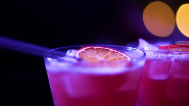 Garnishing a fruity pink cocktail with a piece of dried orange at a nightclub