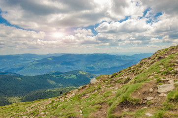 Mountain downhill with stones on the peak of mountain. summer spruce forest on the hills.