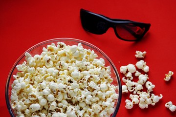 Popcorn for watching a movie in a Cup with 3D glasses on a red background