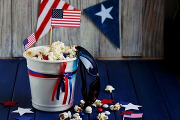 Patriotic popcorn on July 4 in a white bucket with the American flag on a blue wooden background.The US independence day