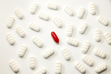 many white pills a red one on white background