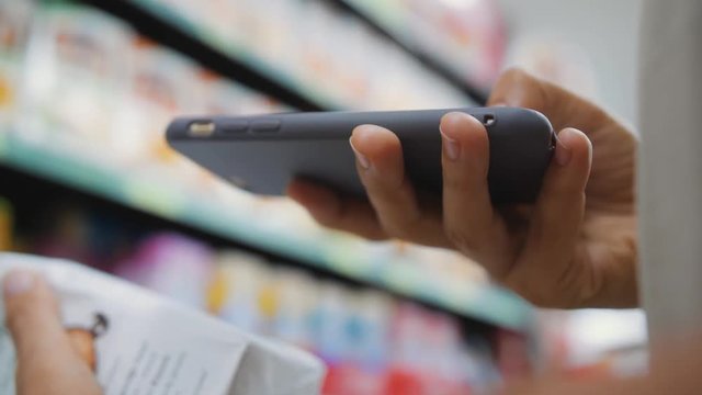 Woman Scanning Product Bar Code in the Shop Using Mobile Phone App. Digital Shopping Future Gadget Consumerism Concept. 4K Slowmotion.