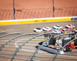 Race track safety fence with blurred cars in background