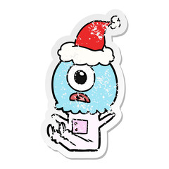 distressed sticker cartoon of a cyclops alien spaceman wearing santa hat