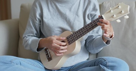 Woman play with ukulele at home