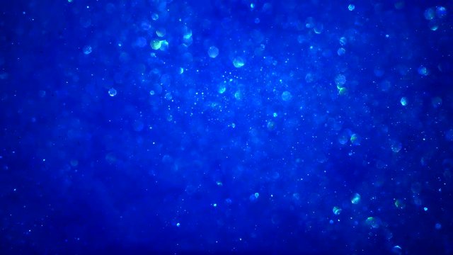 Abstract blue sparkly particle background with bokeh light and shiny frozen crystals in water LOOP.
