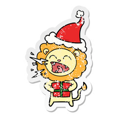 distressed sticker cartoon of a roaring lion with gift wearing santa hat