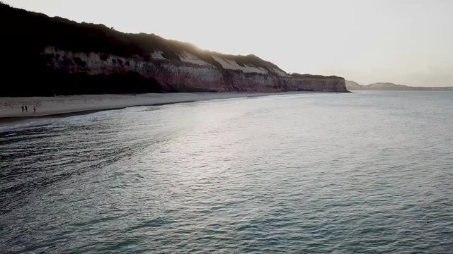 Drone footage. View from above, flying over the beach. Sun over the cliff. Coastline of Praia da pipa, Rio grande do norte, brazil.