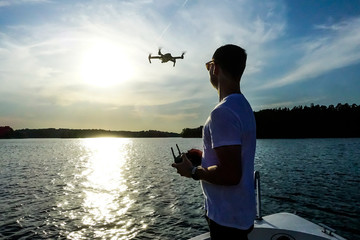 Stockholm, Sweden A man flies his drone over the water from a boat.