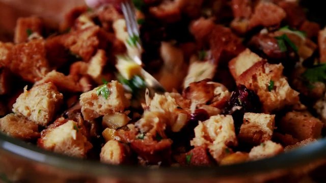 Bread stuffing with mushrooms, dried cranberries, herbs, and onions stirred together in a glass bowl. Great quality and color. 4K