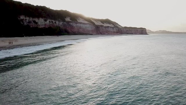 Drone footage. View from above, flying over the beach. Sun over the cliff. Coastline of Praia da pipa, Rio grande do norte, brazil.