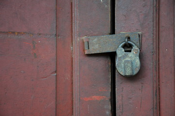 rusty padlock on old red wood door