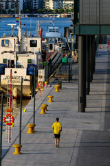 Stockholm, Sweden  A jogger in yellow at the Hammarby shipping lock between the Baltic Sea and Lake Malaren. Hammarby Kaj.
