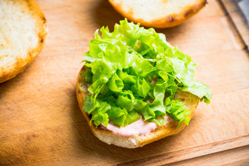 Making burger with fresh buns, meat and salad. Selective focus.