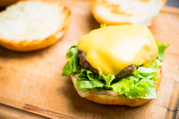 Making burger with fresh buns, meat and salad. Selective focus.