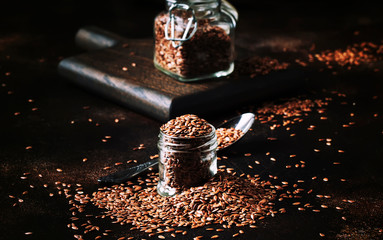 Flax seeds in glass jar, brown kitchen table background, selective focus