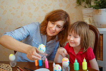 Mom and daughter have fun painting eggs for Easter.