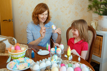 Mom and daughter have fun painting eggs for Easter.